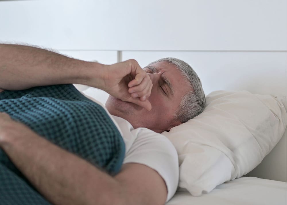 Man coughing in bed